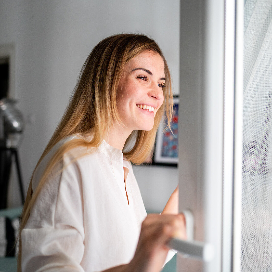 Woman opening window and breathing fresh air Woman opening window and breathing fresh air