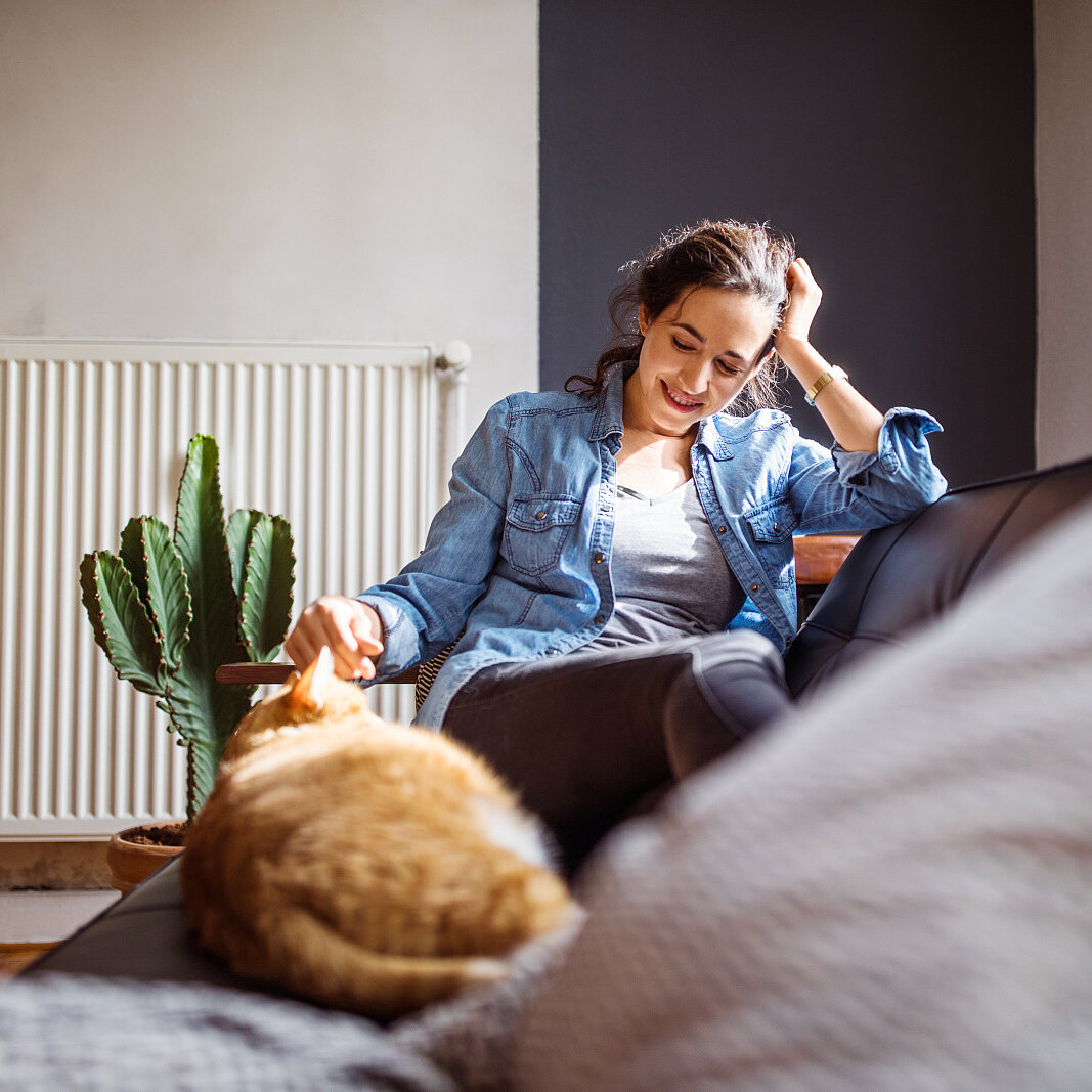 Woman relaxing on sofa with her cat Woman relaxing on sofa, with her cat, in the living room